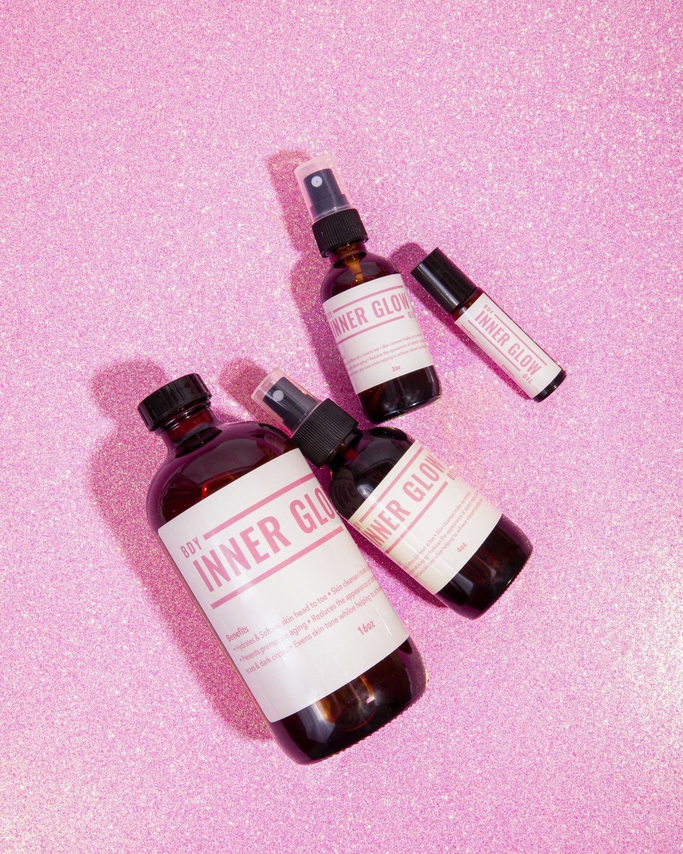 Inner Glow Signature Body Oil family pack on pink glitter background